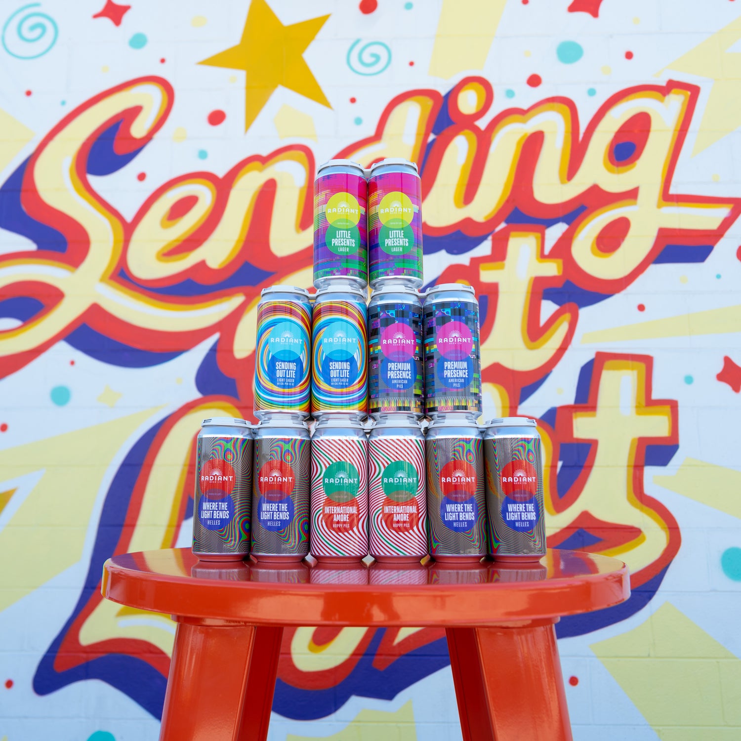 6 4-packs stacked together in front of the Radiant Mural