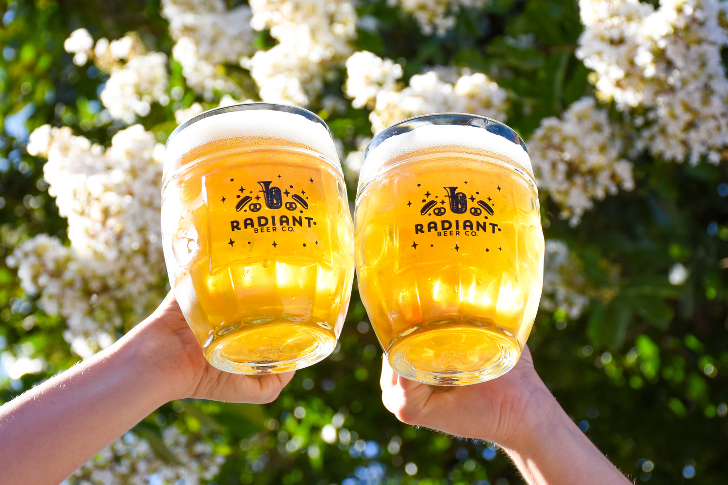 Two Radiant Branded Glasses Cheersing with flowers in the backdrop