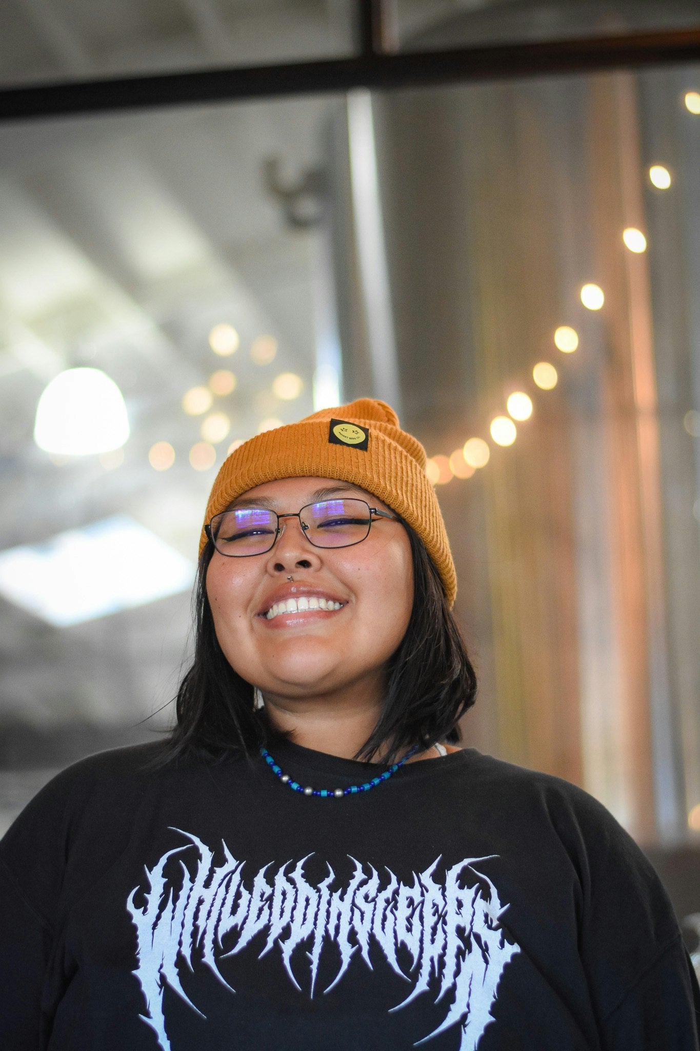 Mustard beanie with a black tag and a yellow smiley face