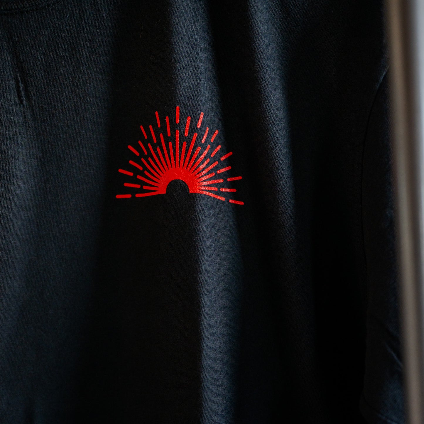 Black shirt with a red logo on a dark background