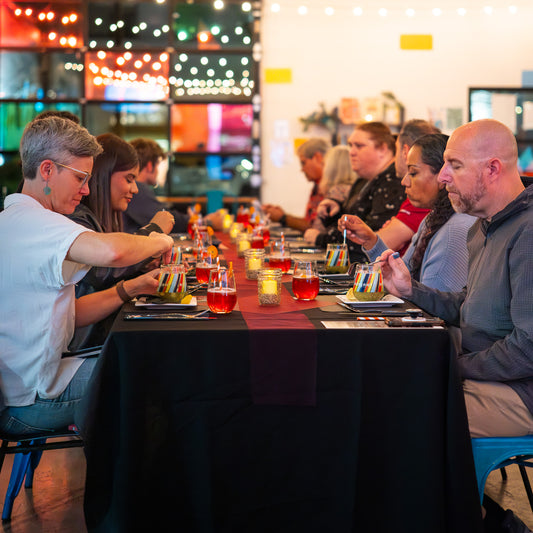 Group of people sitting around a table with colorful drinks and desserts in a festive setting.