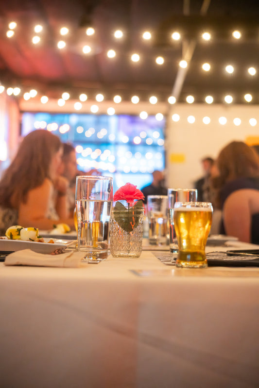 Table setting with drinks and food in a social setting with blurred people in the background