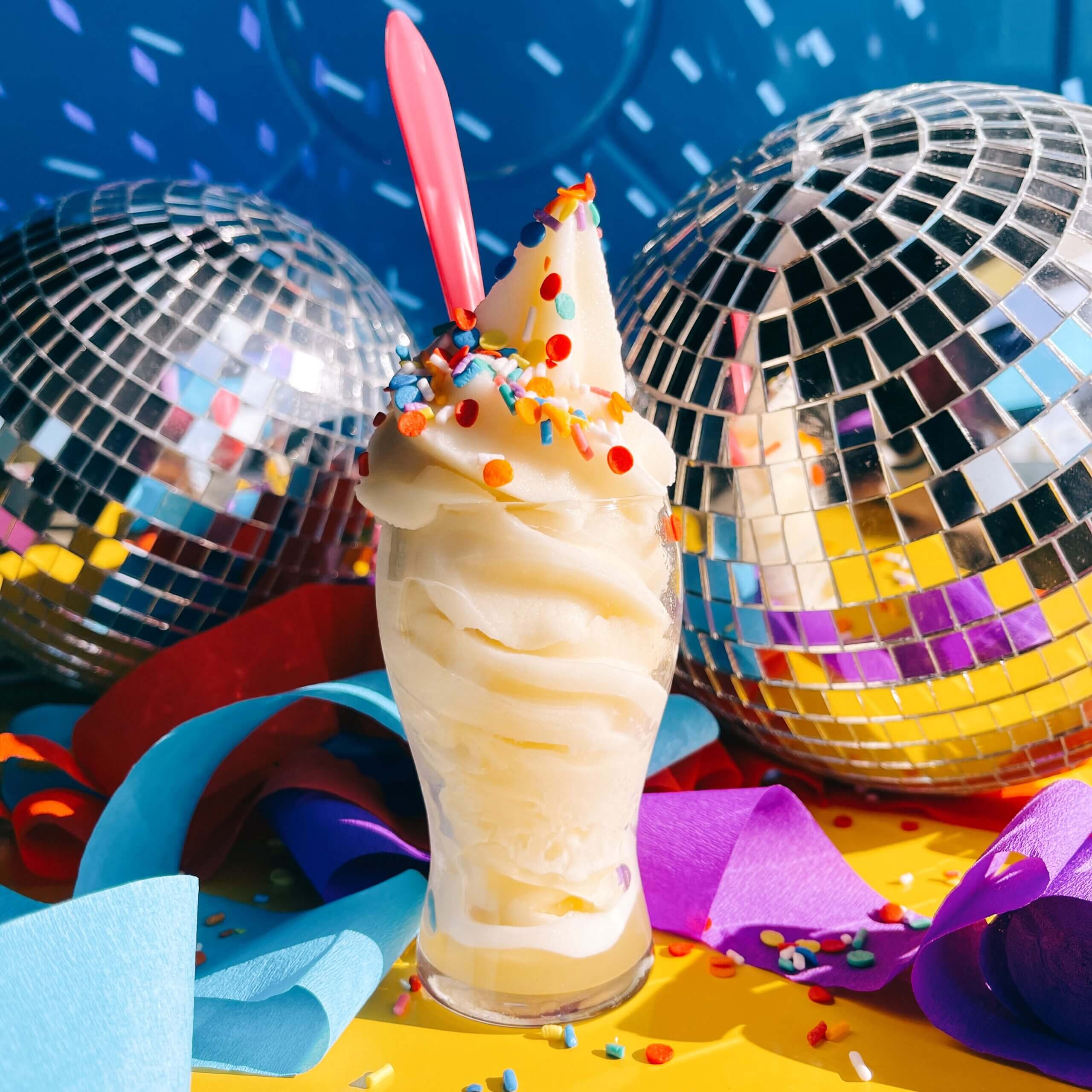 Pale soft serve with sprinkles in front of a disco ball 