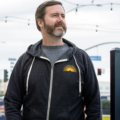 Grey Radiant zip up hoodie with a yellow sunburst on the front 
