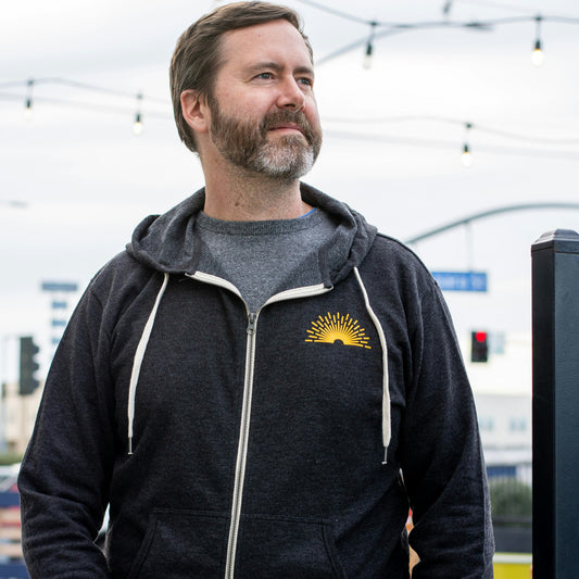Grey Radiant zip up hoodie with a yellow sunburst on the front 