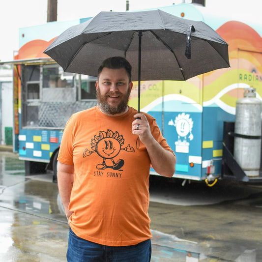 Radiant Team Member stands in a Stay Sunny t-shirt featuring our mascot sunny. 