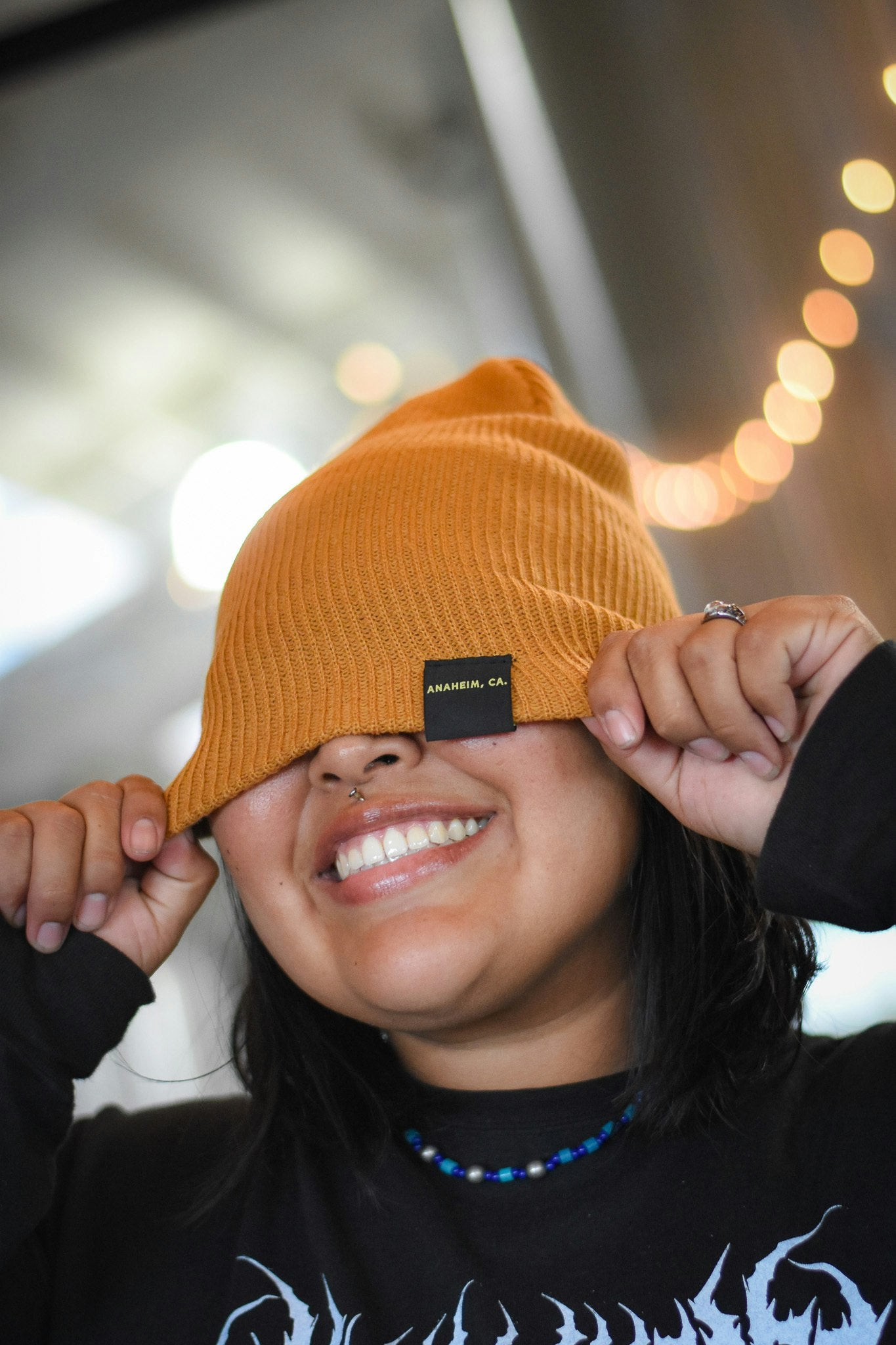 A staff member wears a mustard colored beanie with the tag showing Anaheim CA